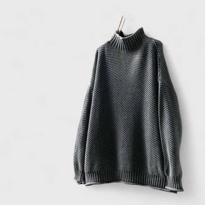 Grå strikket sweater med højhals og struktureret overflade vist på knage mod hvid baggrund_0