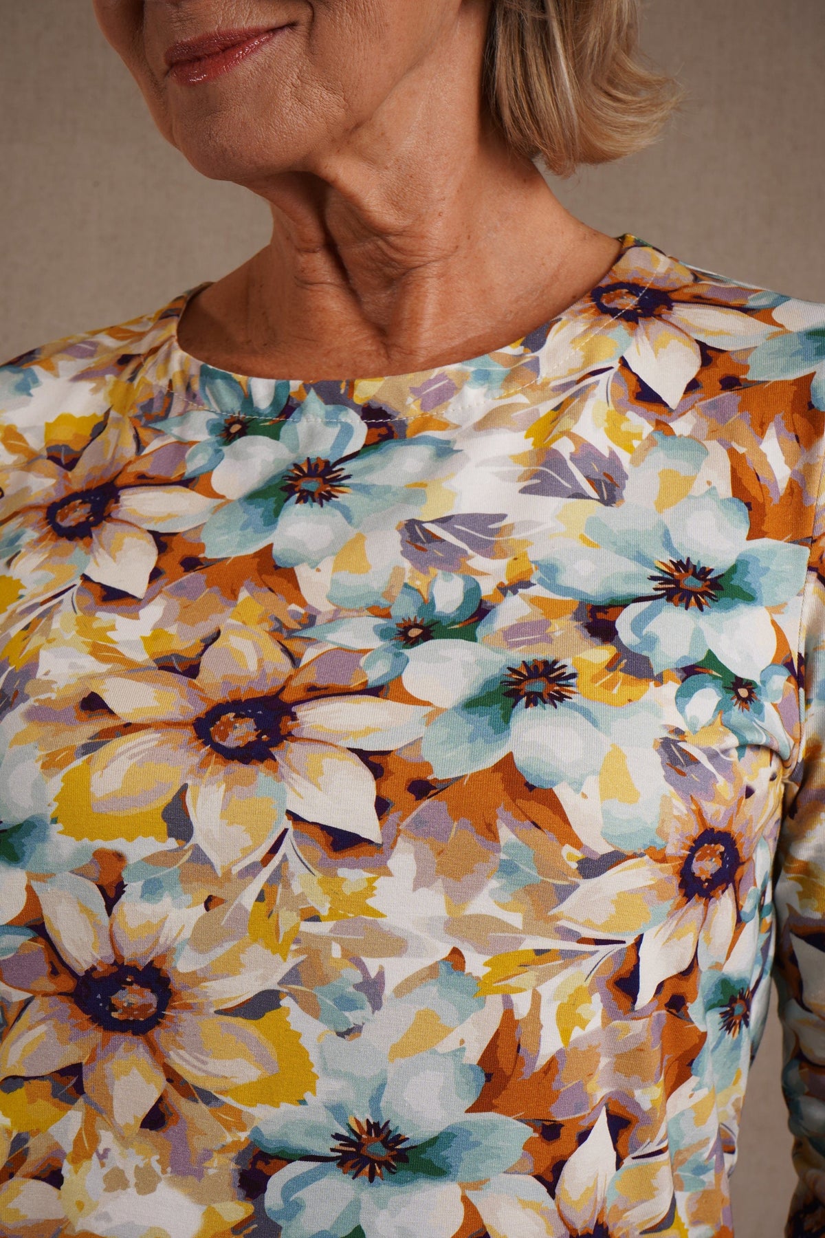 Kvinde i bluse med blomsterprint, rund halsudskæring og 3/4 ærmer._2