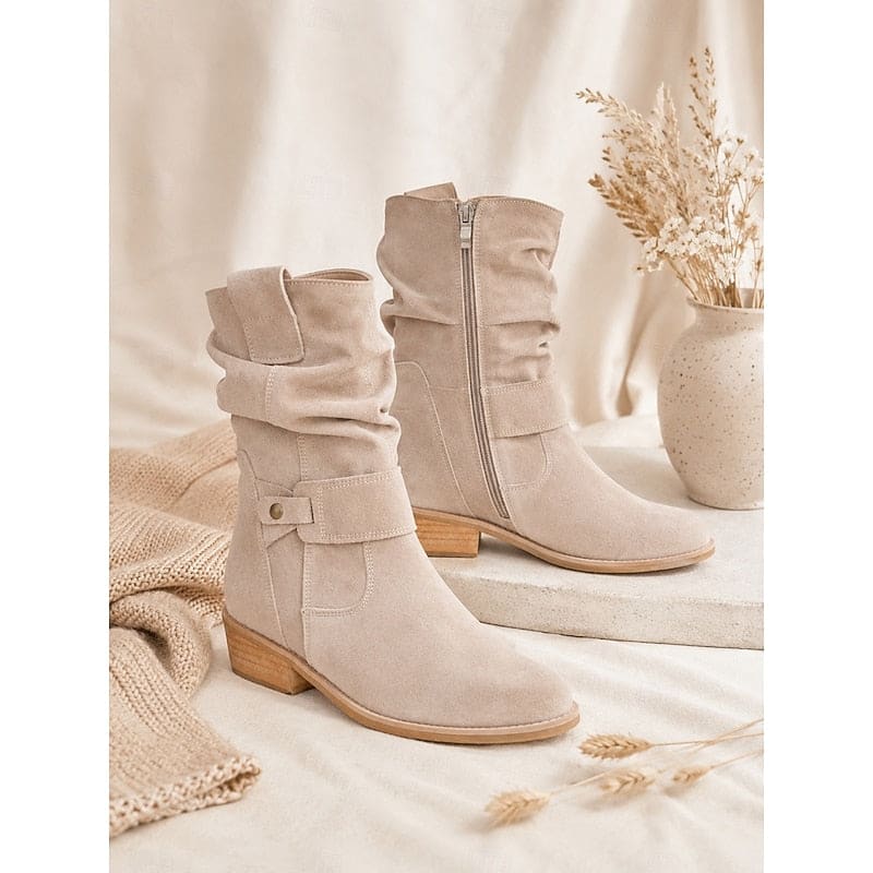 Kvinde bærer beige ankelstøvler med slouchy skaft, blokhæl og spændedetalje på flisegulv._6