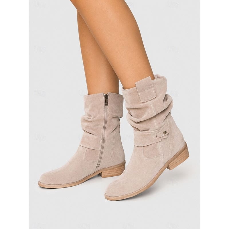 Kvinde bærer beige ankelstøvler med slouchy skaft, blokhæl og spændedetalje på flisegulv._7