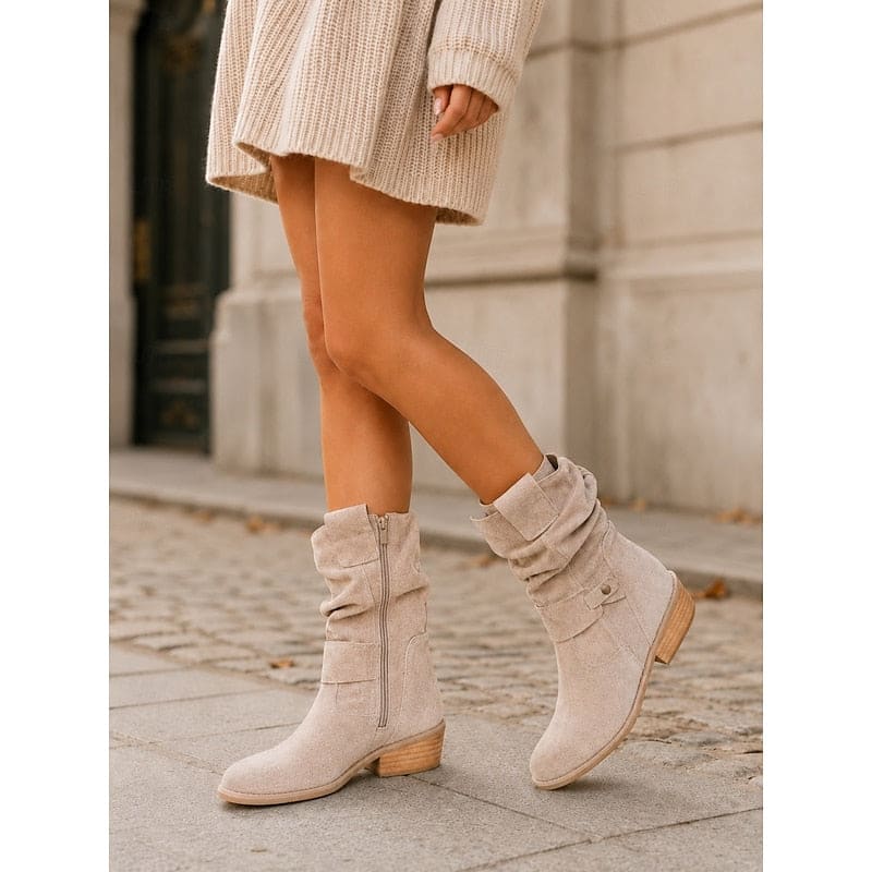 Kvinde bærer beige ankelstøvler med slouchy skaft, blokhæl og spændedetalje på flisegulv._8