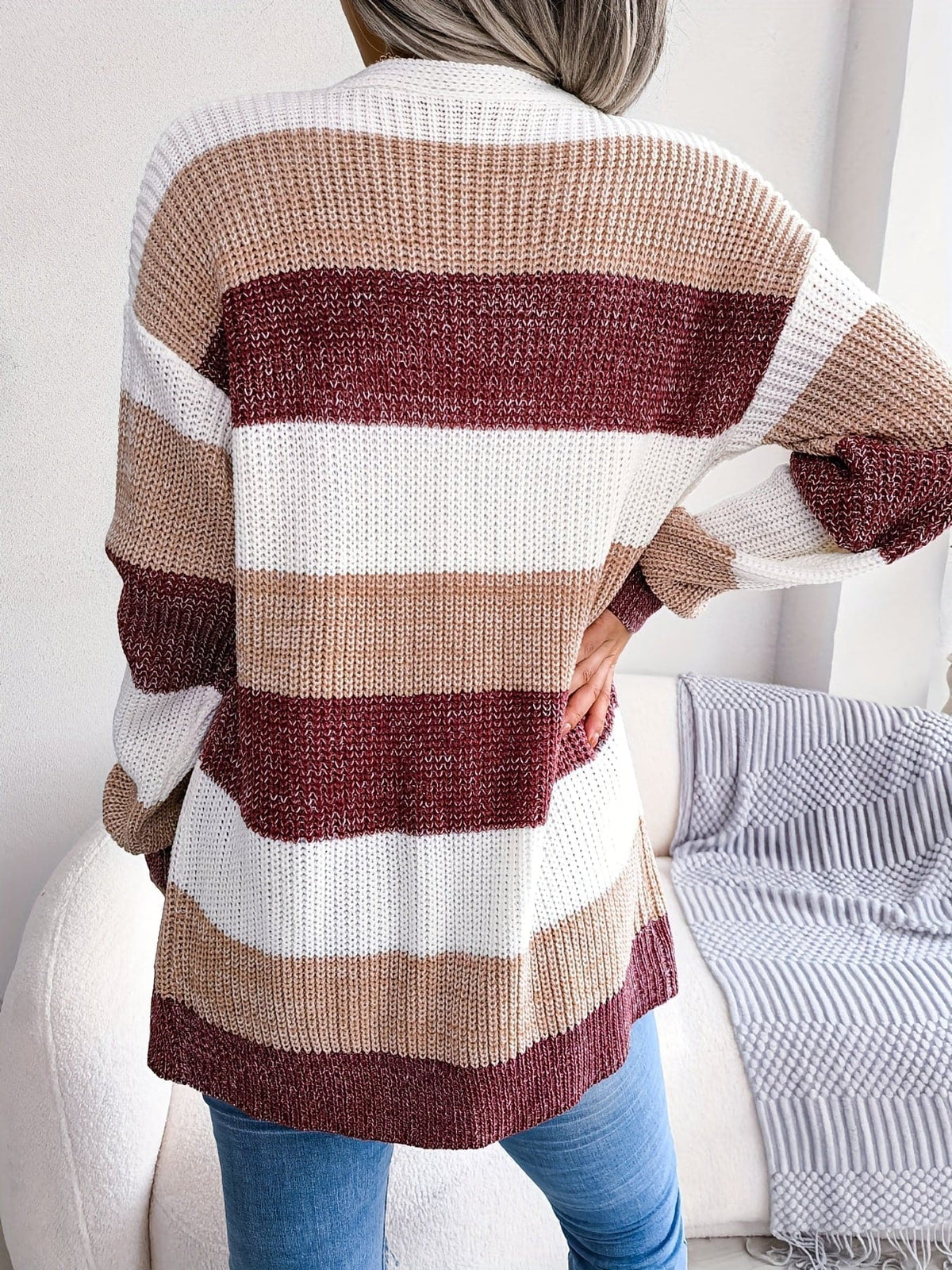 Kvinde iført stribemønstret cardigan med lommer over hvid top og blå jeans._12