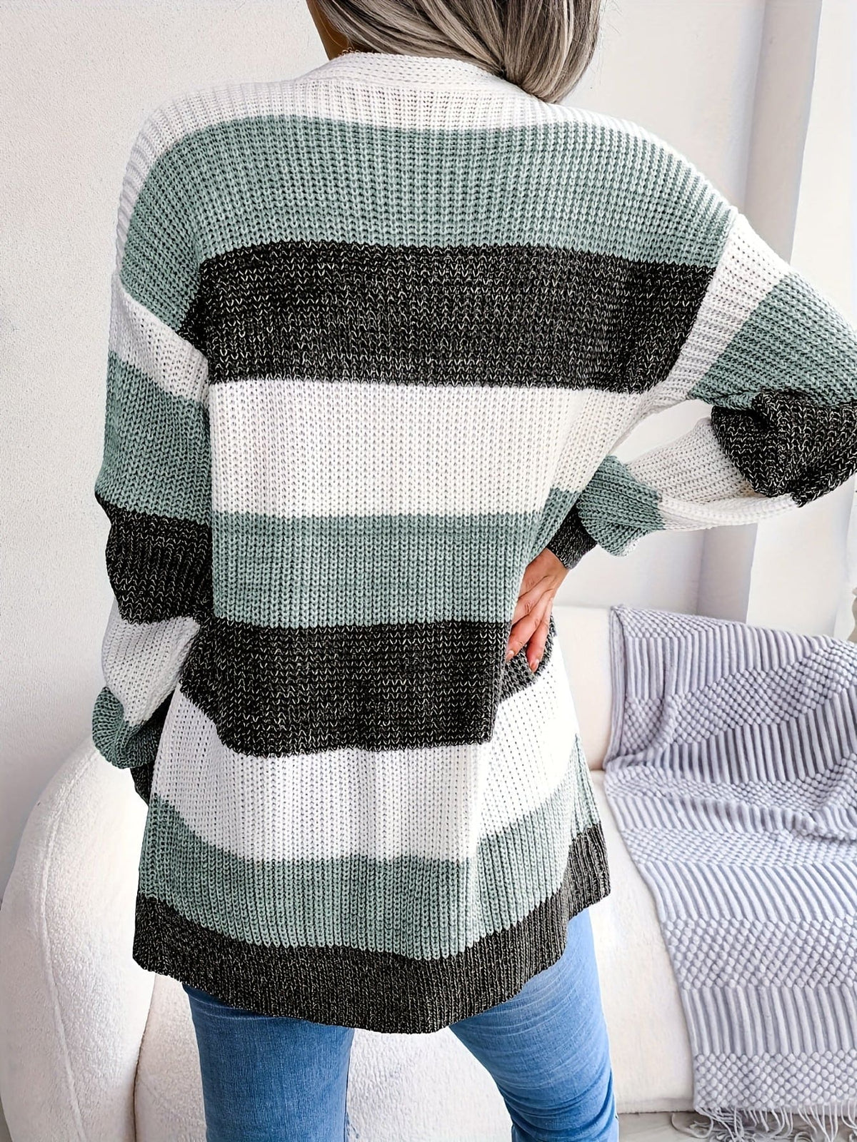 Kvinde iført stribemønstret cardigan med lommer over hvid top og blå jeans._5