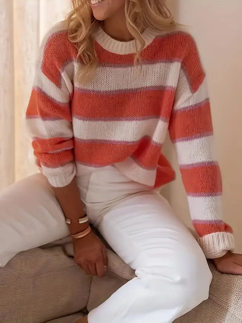 Kvinde iført stribet sweater i coral, beige og hvid med rund hals og afslappet pasform._1