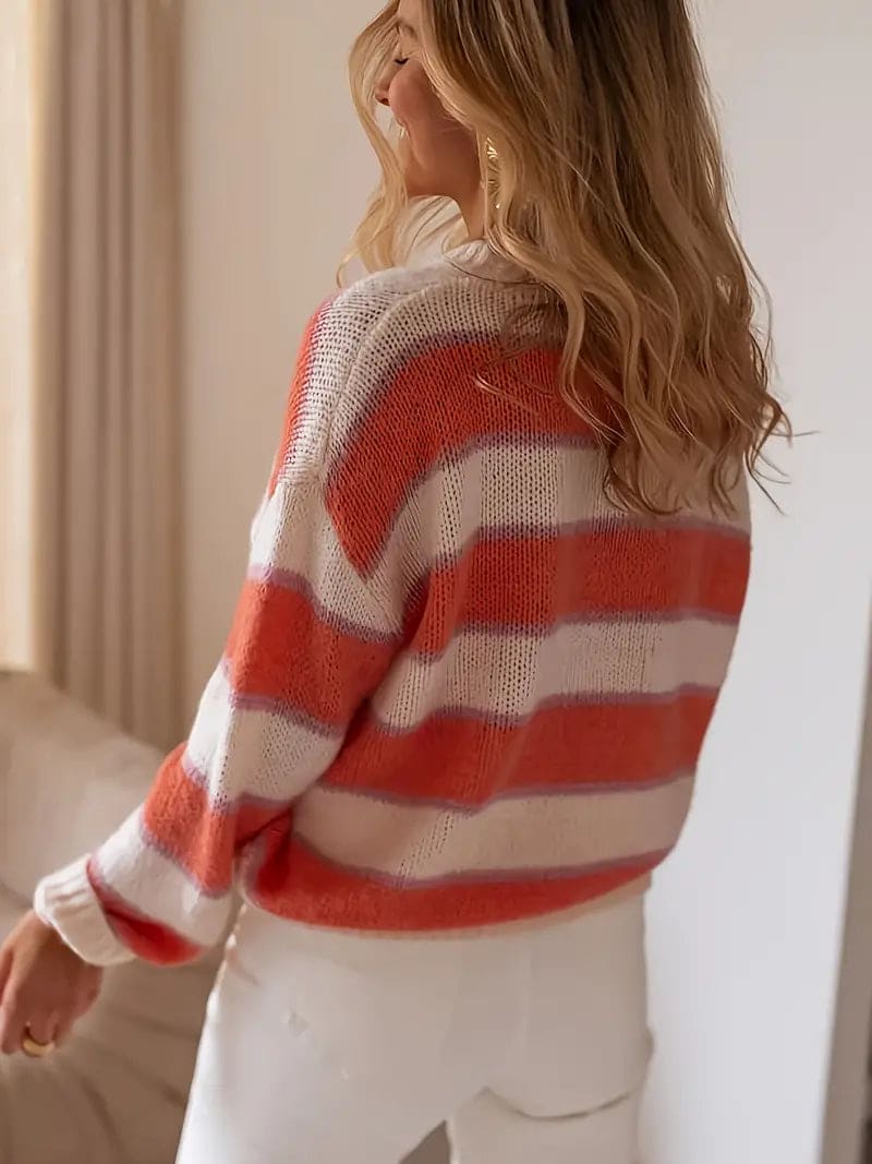 Kvinde iført stribet sweater i coral, beige og hvid med rund hals og afslappet pasform._2