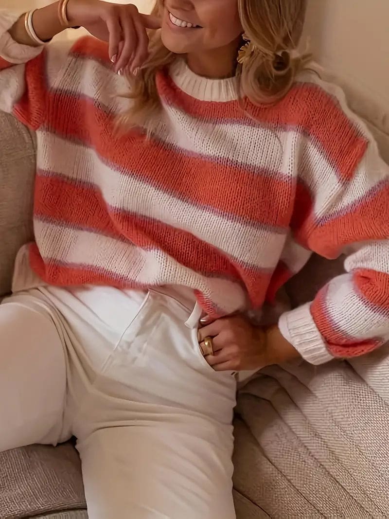 Kvinde iført stribet sweater i coral, beige og hvid med rund hals og afslappet pasform._3