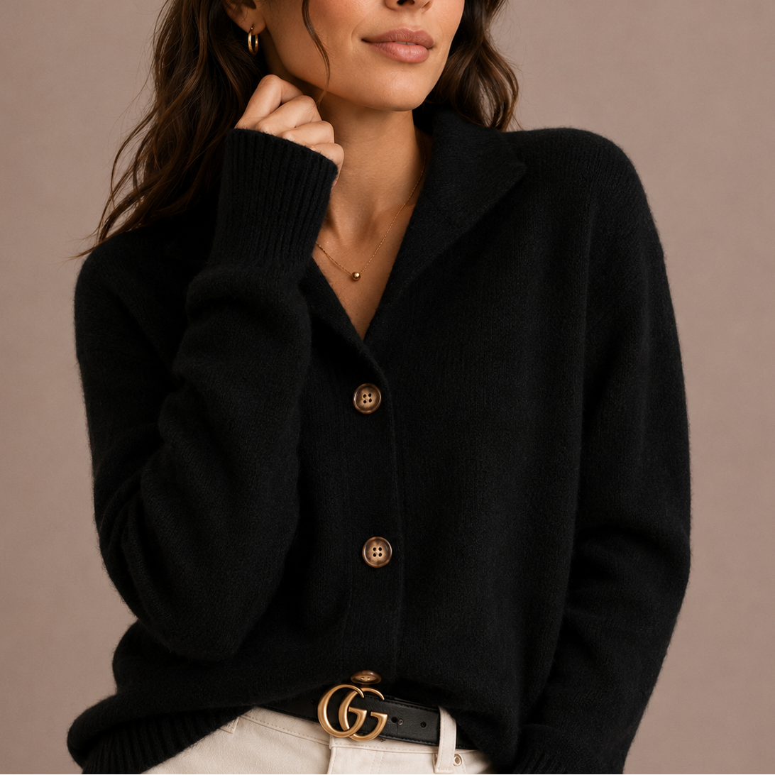 Model iført sort strikket cardigan med krave og knaplukning i front, styled med hvid nederdel og bælte._0