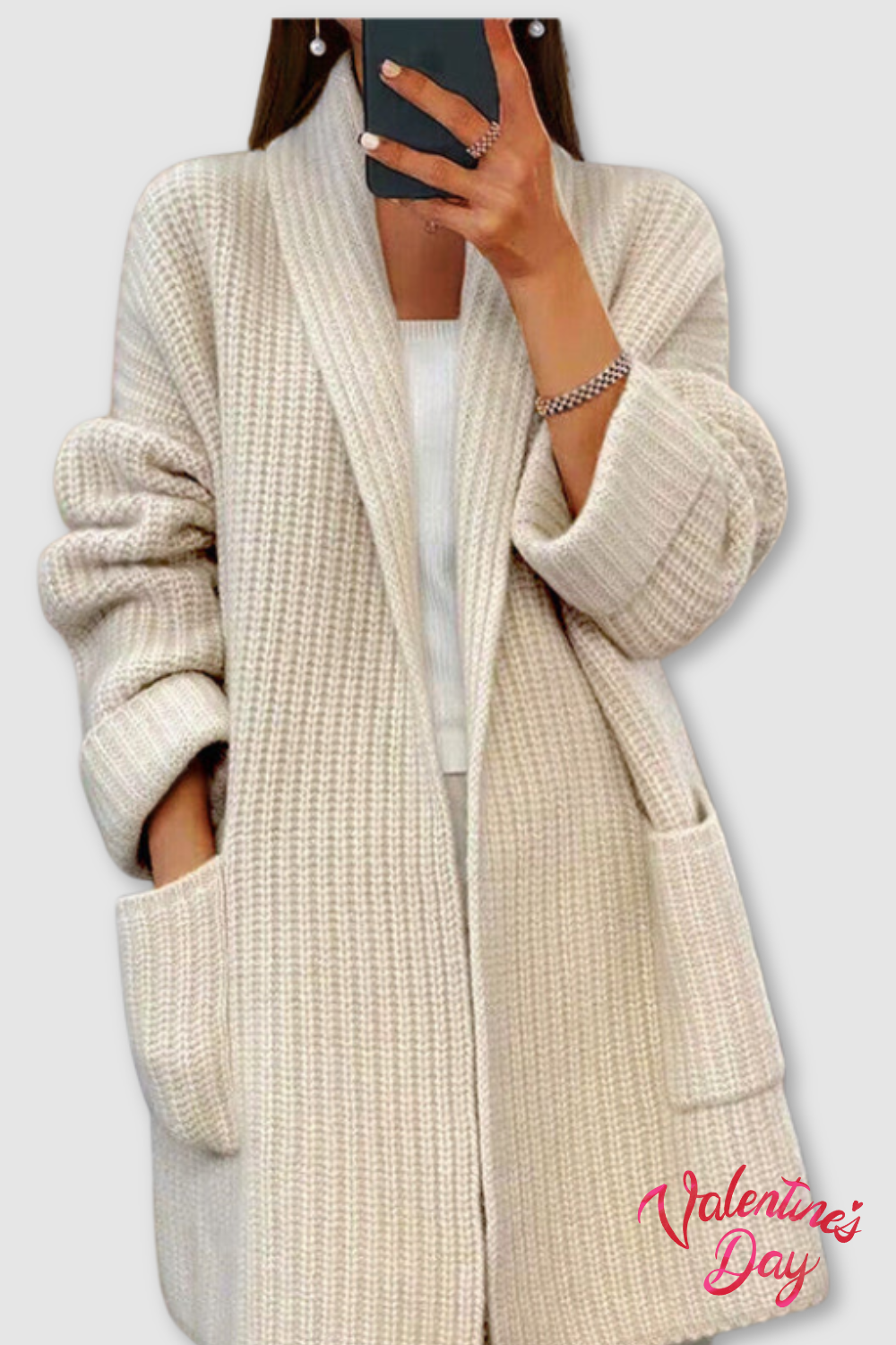 Kvinde iført en lang, beige strikket cardigan med åben front, lommer og afslappet pasform, fotograferet i et spejl._0