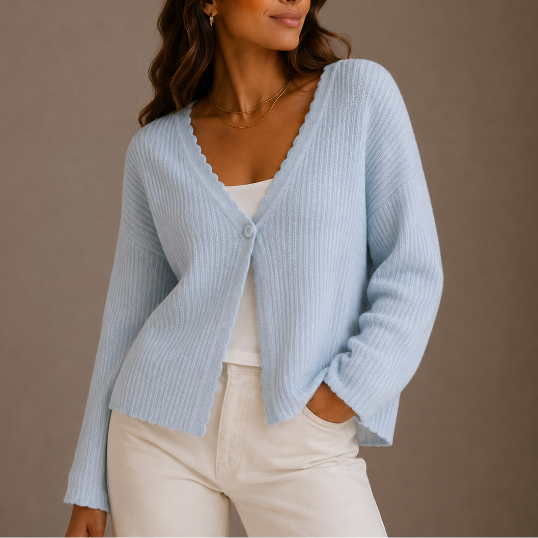 Dame iført en lyseblå strikket cardigan med v-hals og knaplukning, stylet over en hvid top og lyse bukser._0