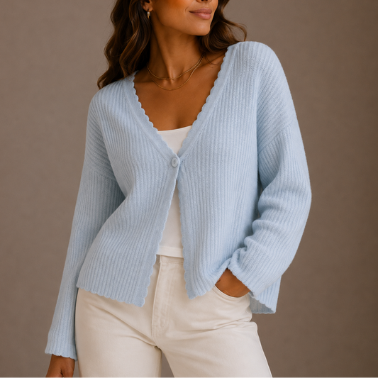 Dame iført en lyseblå strikket cardigan med v-hals og knaplukning, stylet over en hvid top og lyse bukser._0