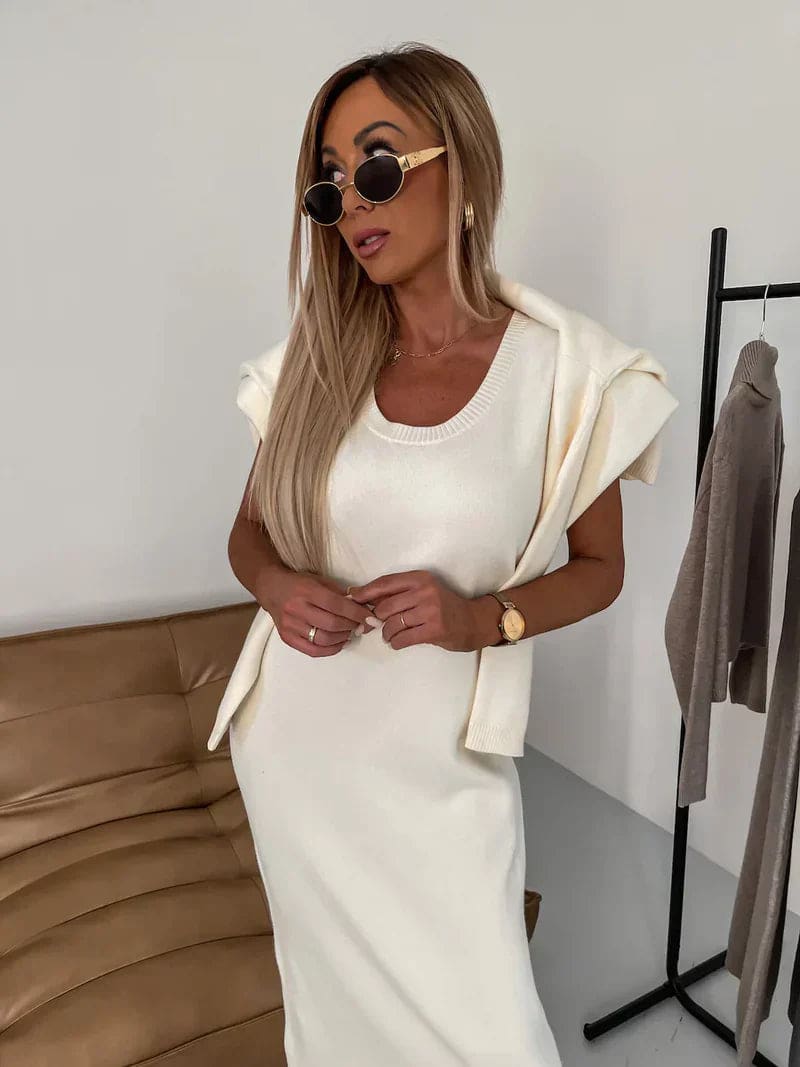 Model iført et hvidt strikket co-ord sæt bestående af en cropped jumper med høj hals og en lang nederdel, stylet med beige støvler og solbriller_1