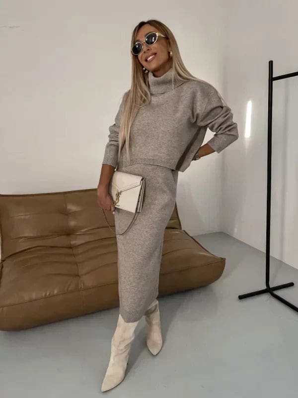 Model iført et hvidt strikket co-ord sæt bestående af en cropped jumper med høj hals og en lang nederdel, stylet med beige støvler og solbriller_6