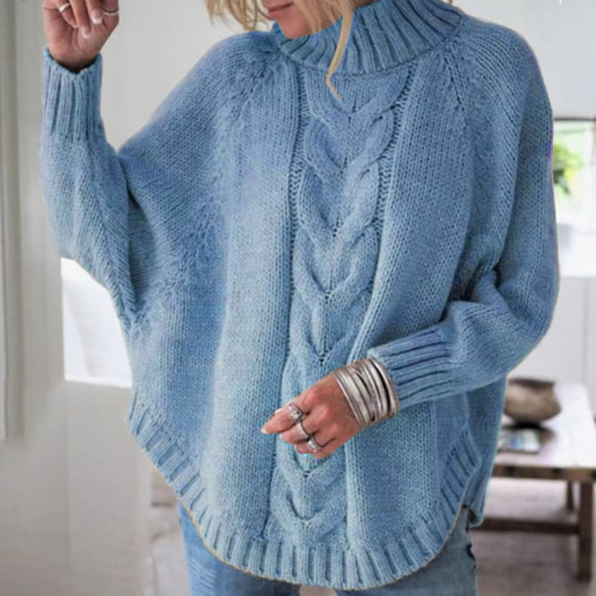 Kvinde iført en lyseblå strikket pullover med høj hals og snoninger i fronten._0