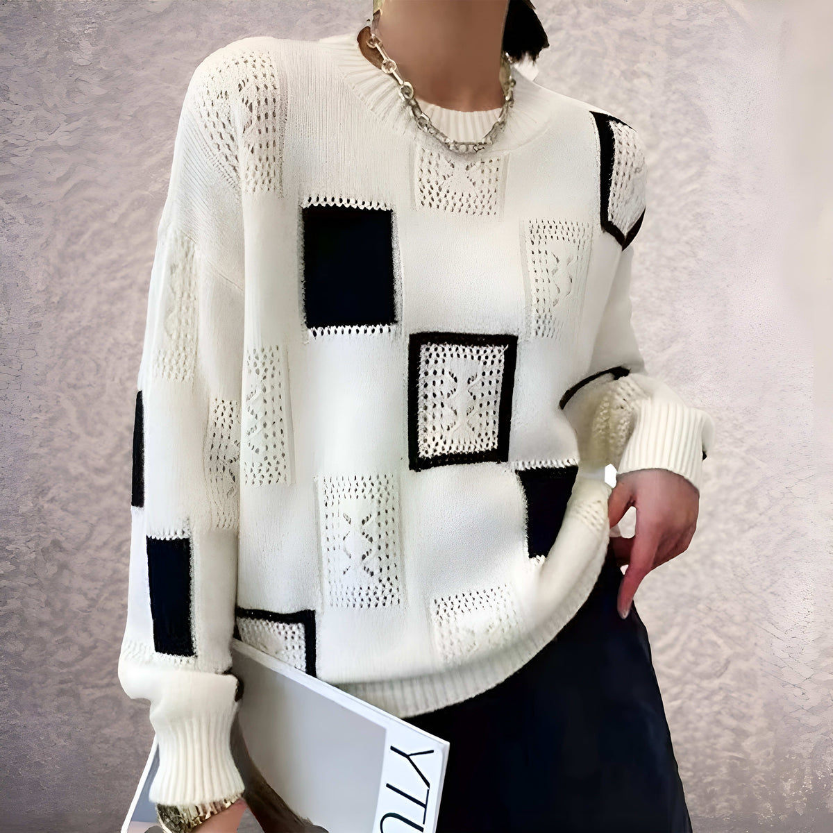 Kvinde iført hvid strikket sweater med sorte geometriske blokke i grafisk mønster og rund hals._1