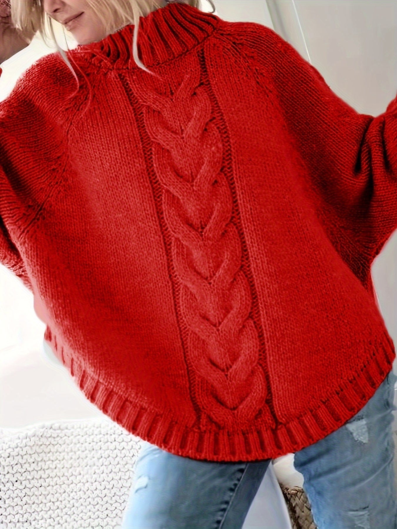Kvinde iført grå strikket sweater med høj hals og kabelmønster, stylet med sølvfarvede armbånd og lyse jeans._8