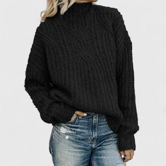 Kvinde iført sort strikket sweater med høj hals og kabelmønster, stylet med lyse jeans._0
