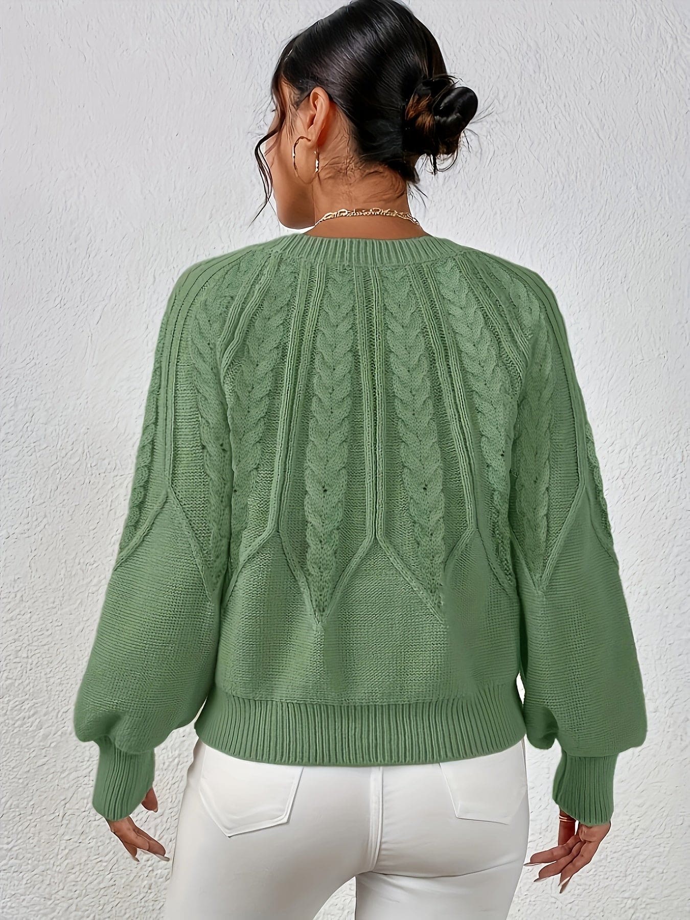 Kvinde set bagfra iført strikket sweater med kabelmønster og ballonærmer._0