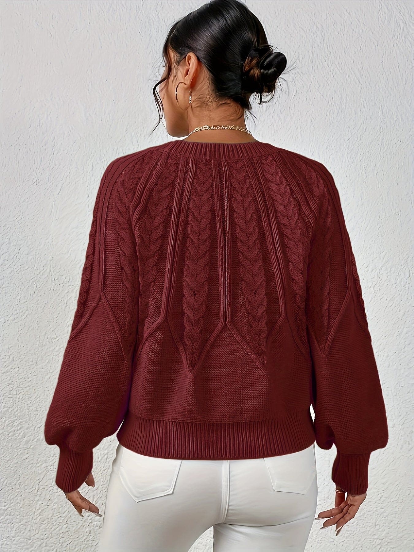 Kvinde set bagfra iført strikket sweater med kabelmønster og ballonærmer._10