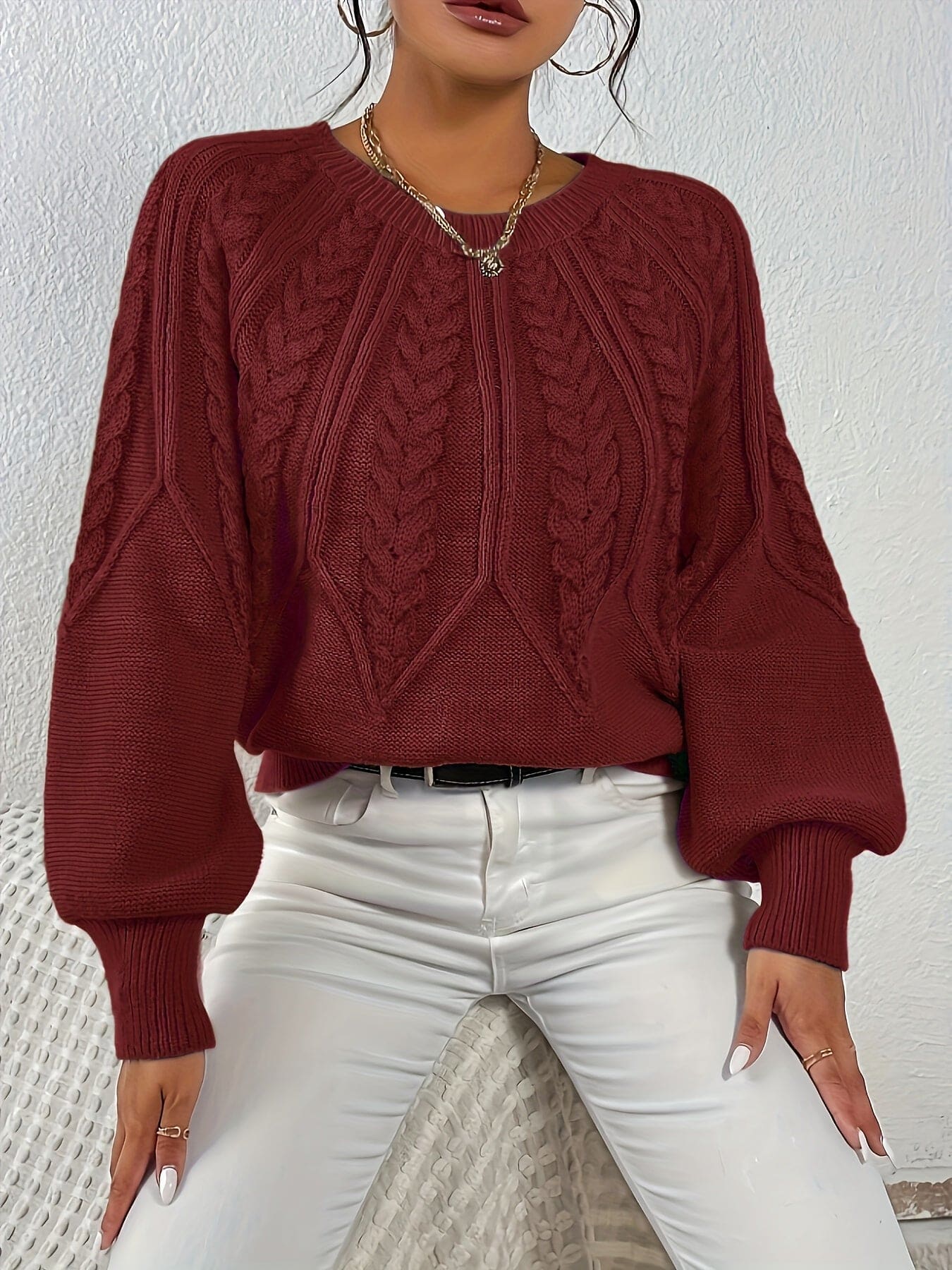 Kvinde set bagfra iført strikket sweater med kabelmønster og ballonærmer._11