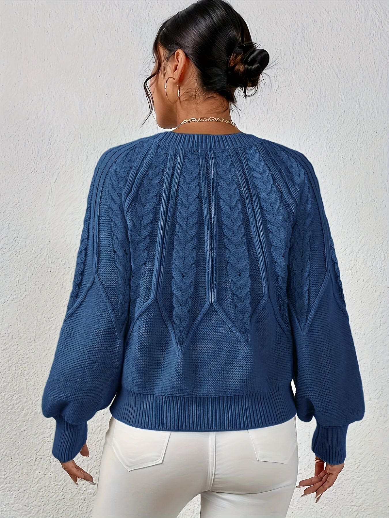 Kvinde set bagfra iført strikket sweater med kabelmønster og ballonærmer._15