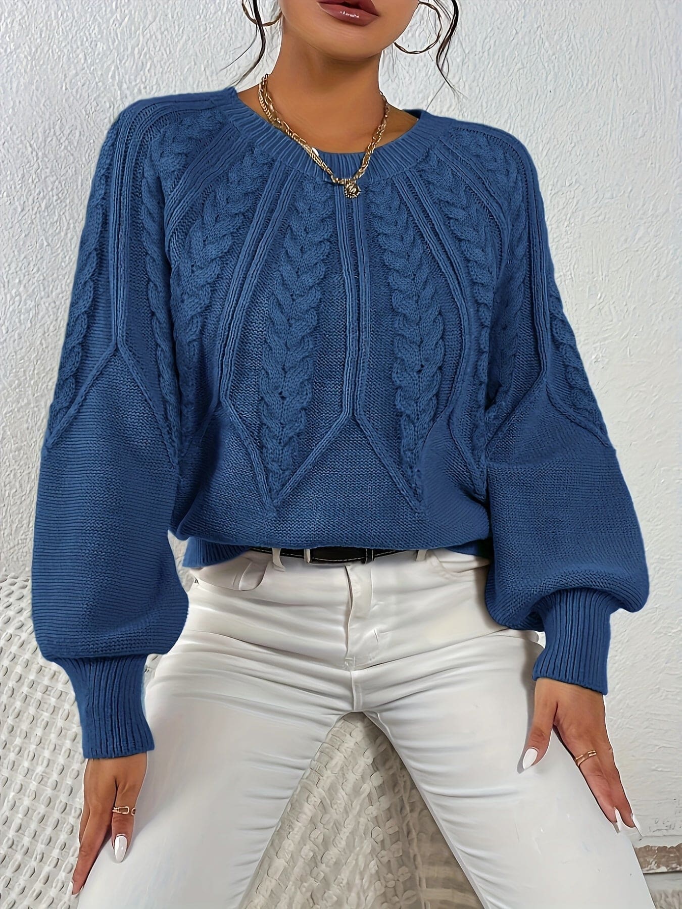 Kvinde set bagfra iført strikket sweater med kabelmønster og ballonærmer._16