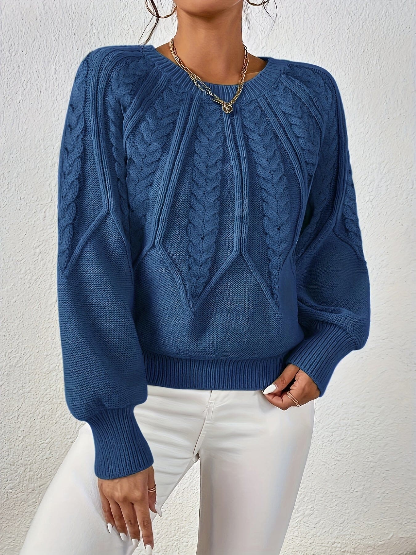 Kvinde set bagfra iført strikket sweater med kabelmønster og ballonærmer._17