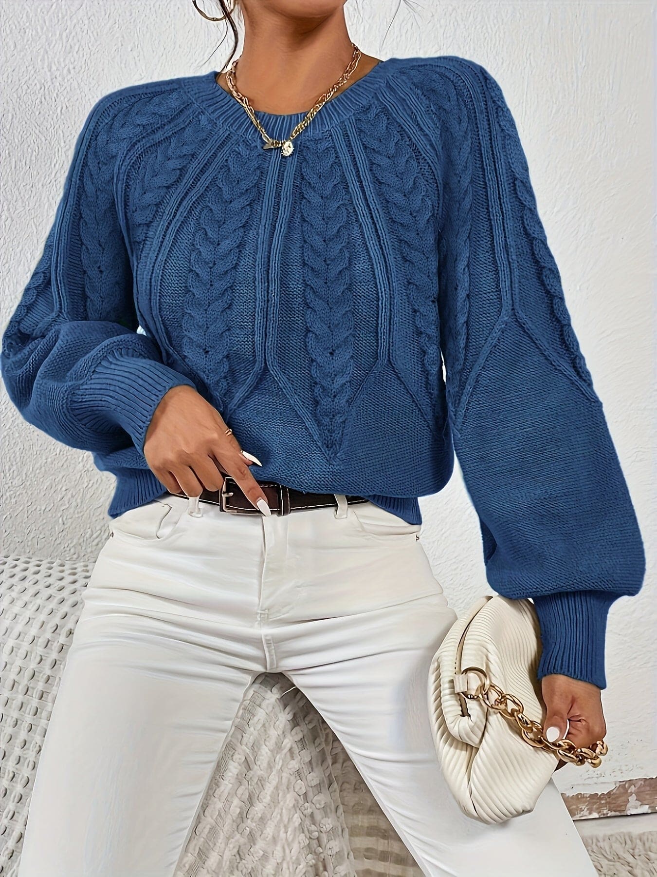 Kvinde set bagfra iført strikket sweater med kabelmønster og ballonærmer._18