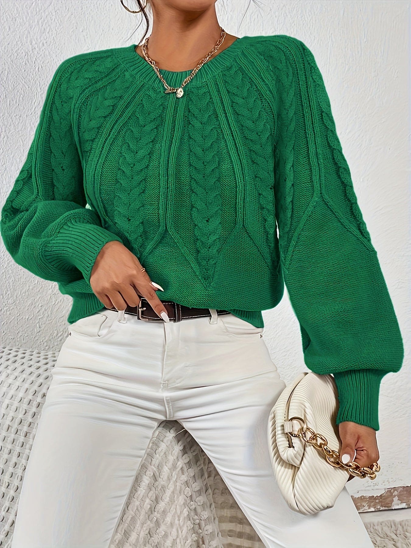 Kvinde set bagfra iført strikket sweater med kabelmønster og ballonærmer._23