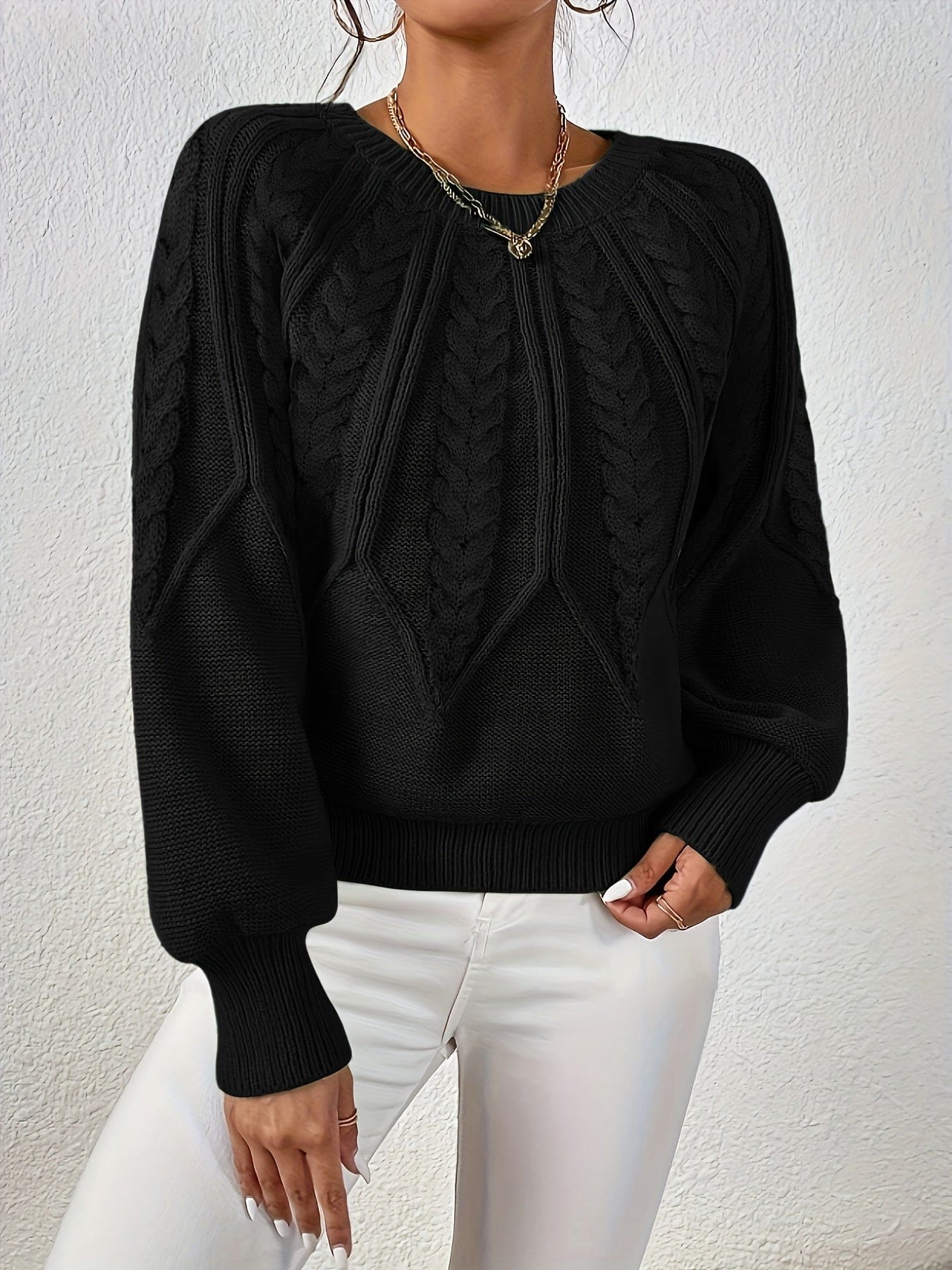 Kvinde set bagfra iført strikket sweater med kabelmønster og ballonærmer._24