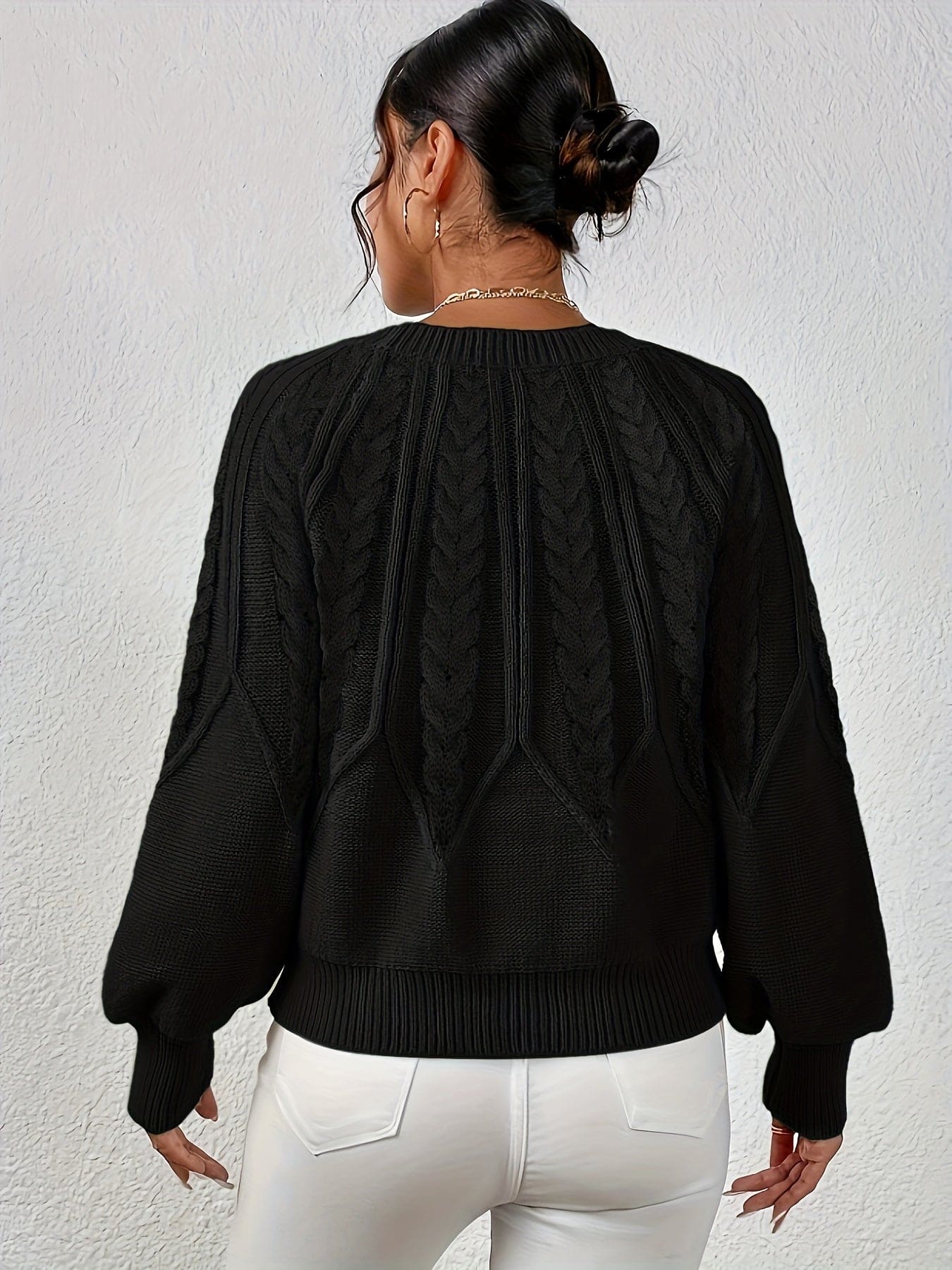 Kvinde set bagfra iført strikket sweater med kabelmønster og ballonærmer._25