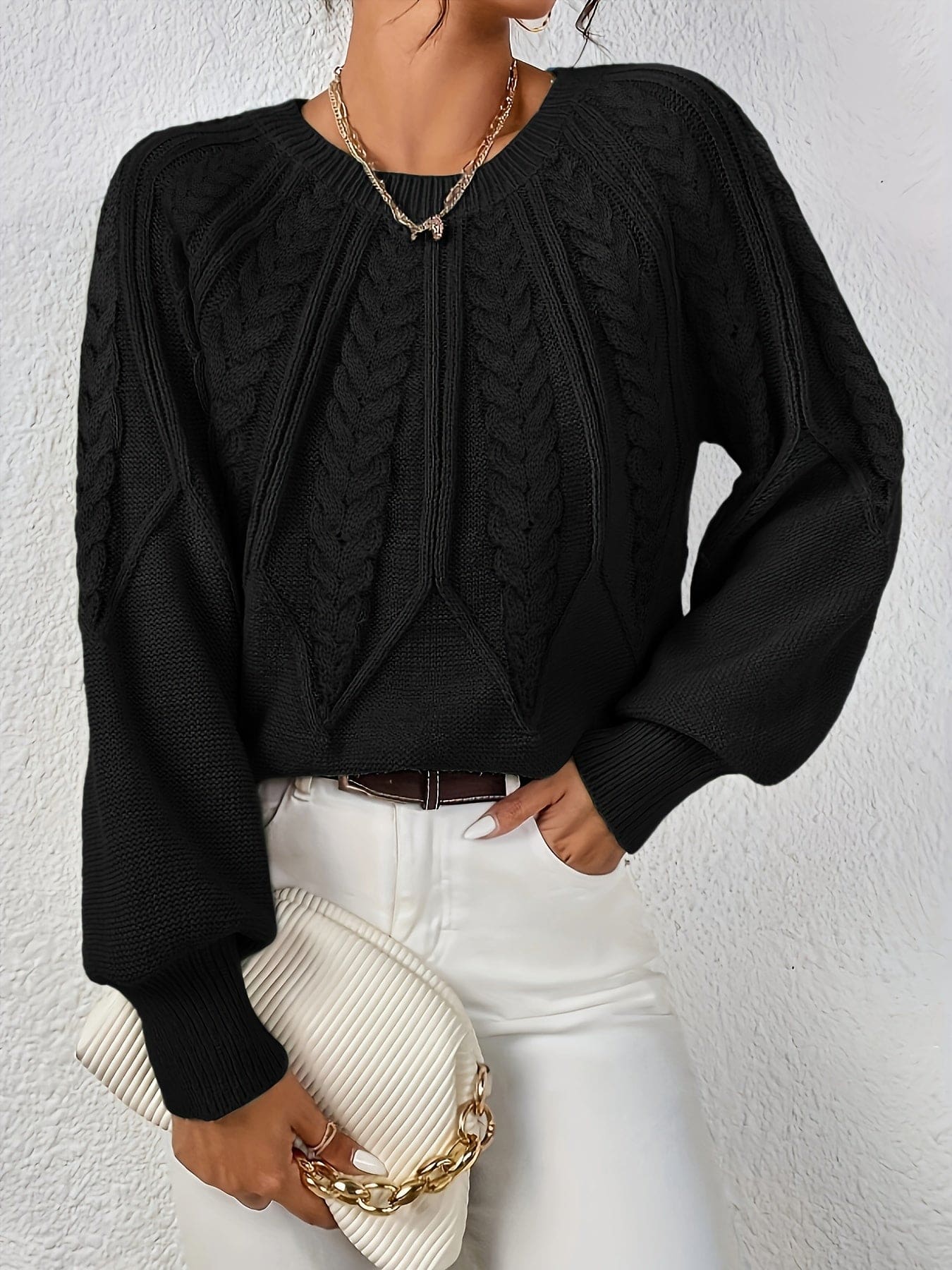 Kvinde set bagfra iført strikket sweater med kabelmønster og ballonærmer._26