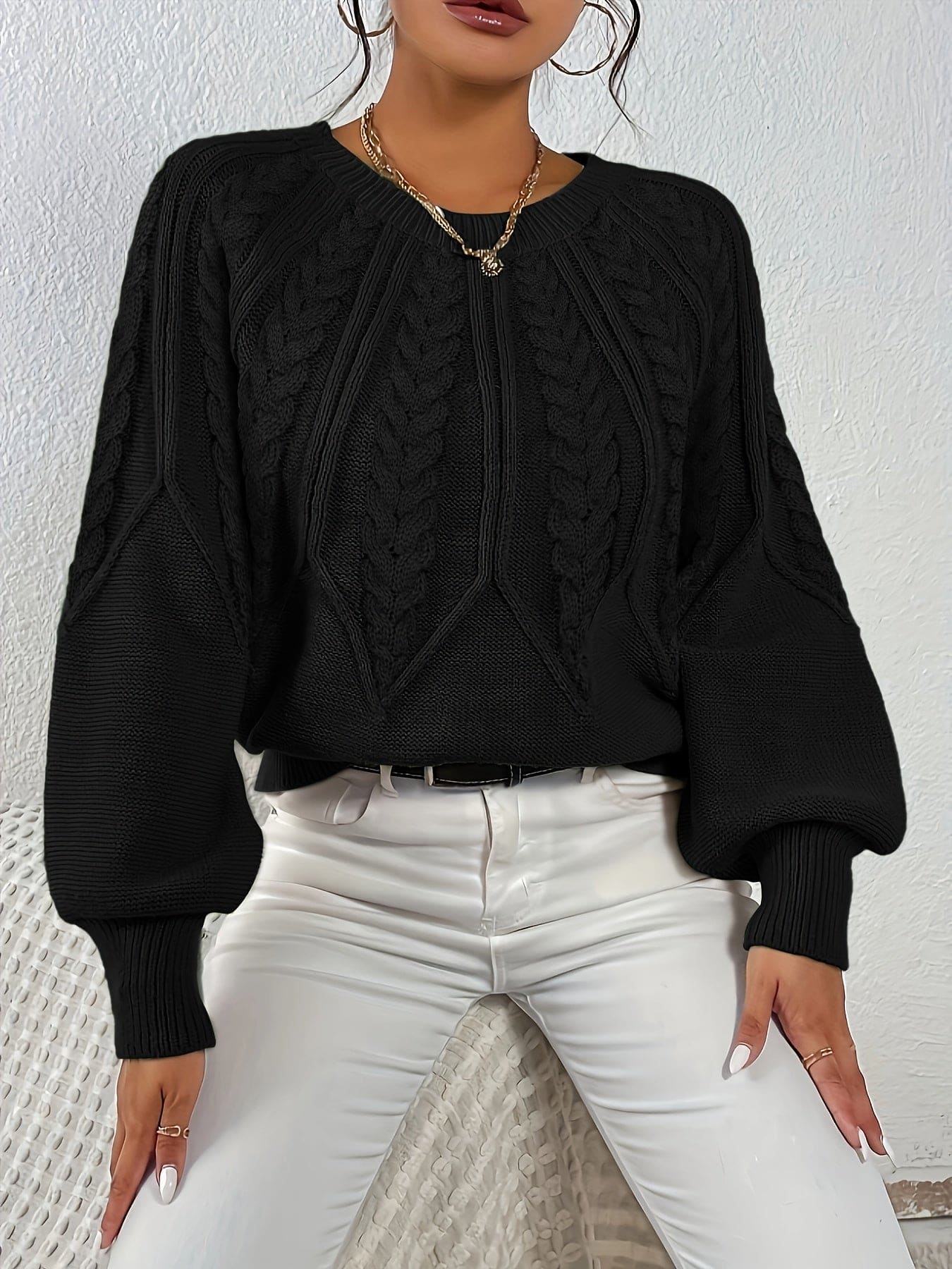 Kvinde set bagfra iført strikket sweater med kabelmønster og ballonærmer._27
