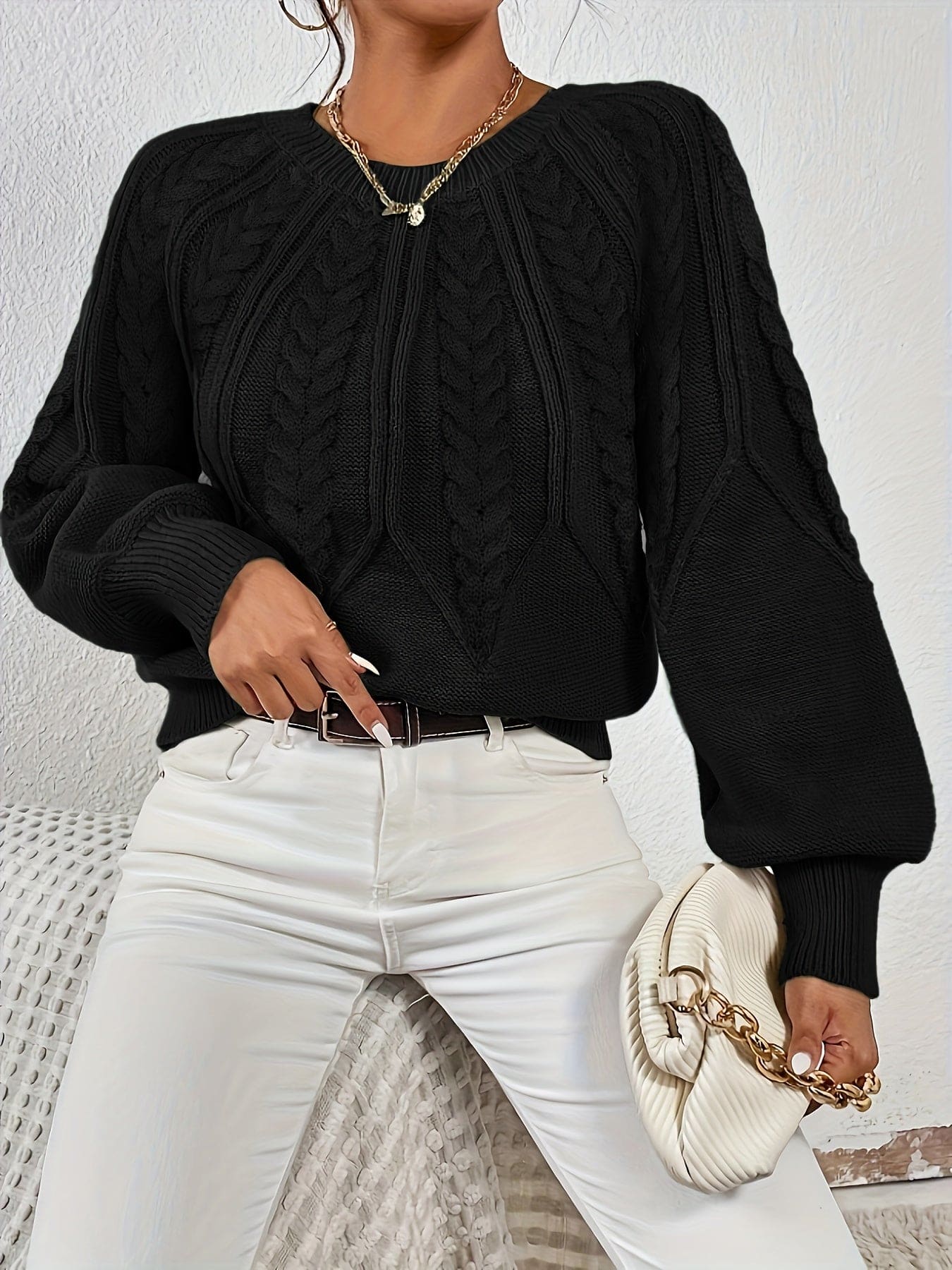 Kvinde set bagfra iført strikket sweater med kabelmønster og ballonærmer._28
