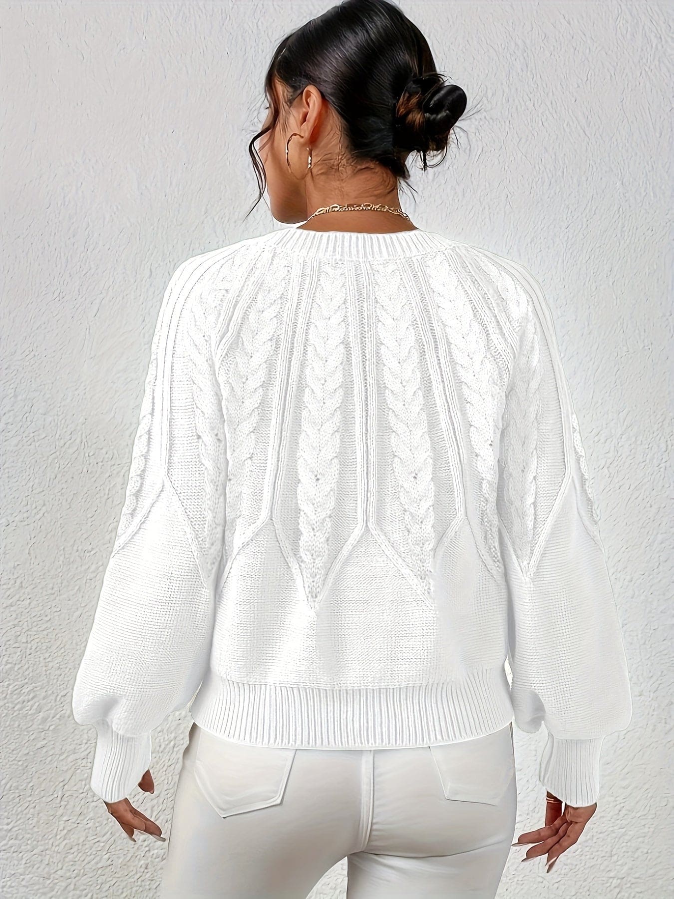 Kvinde set bagfra iført strikket sweater med kabelmønster og ballonærmer._30