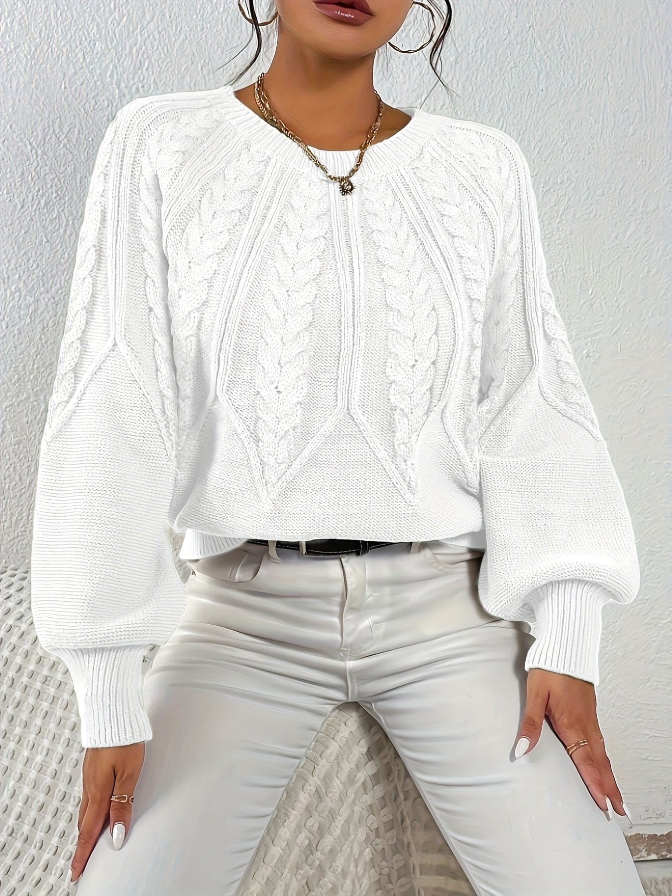 Kvinde set bagfra iført strikket sweater med kabelmønster og ballonærmer._32