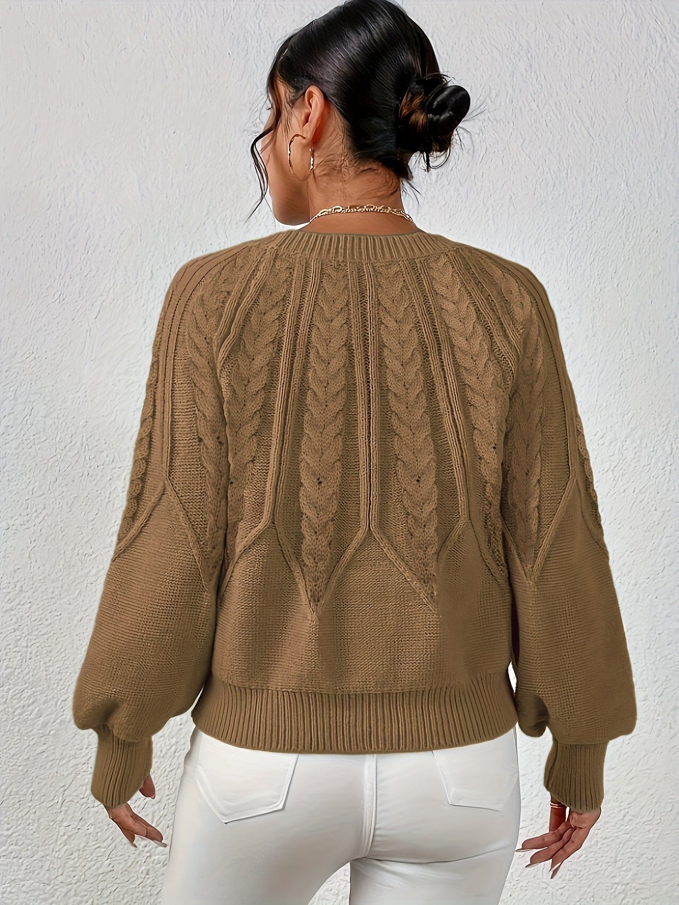 Kvinde set bagfra iført strikket sweater med kabelmønster og ballonærmer._35