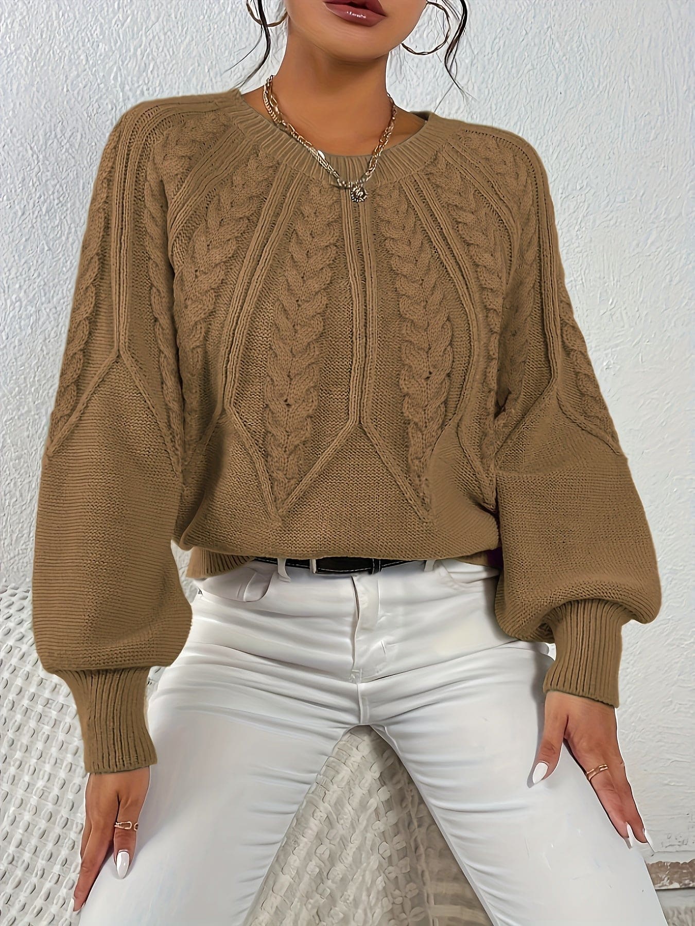 Kvinde set bagfra iført strikket sweater med kabelmønster og ballonærmer._36