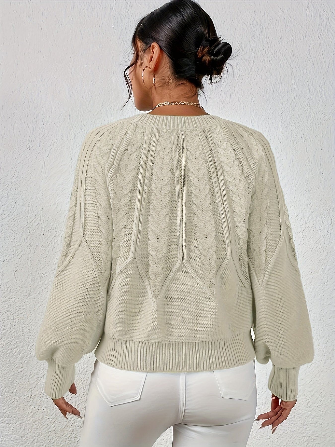 Kvinde set bagfra iført strikket sweater med kabelmønster og ballonærmer._5