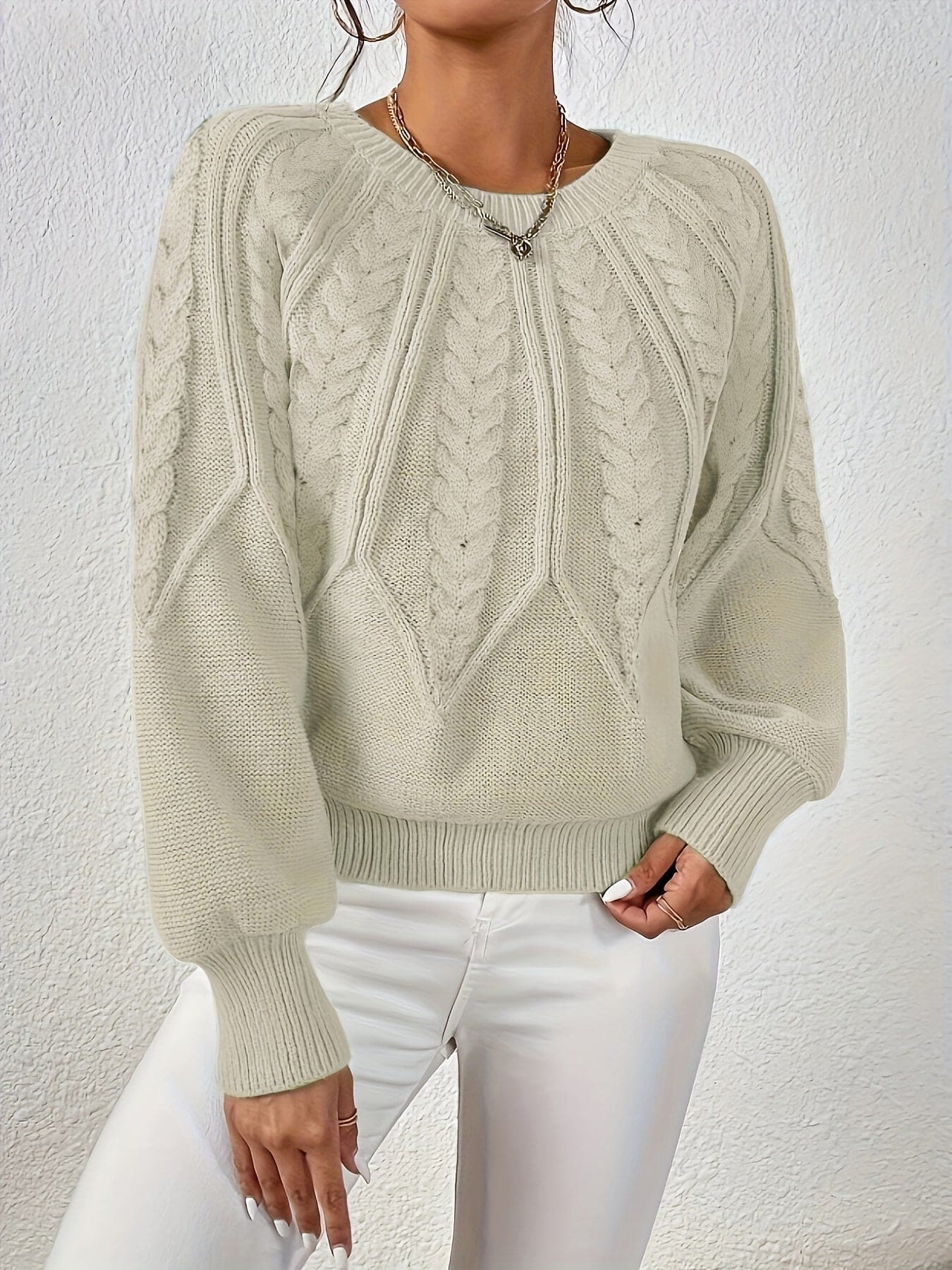 Kvinde set bagfra iført strikket sweater med kabelmønster og ballonærmer._7