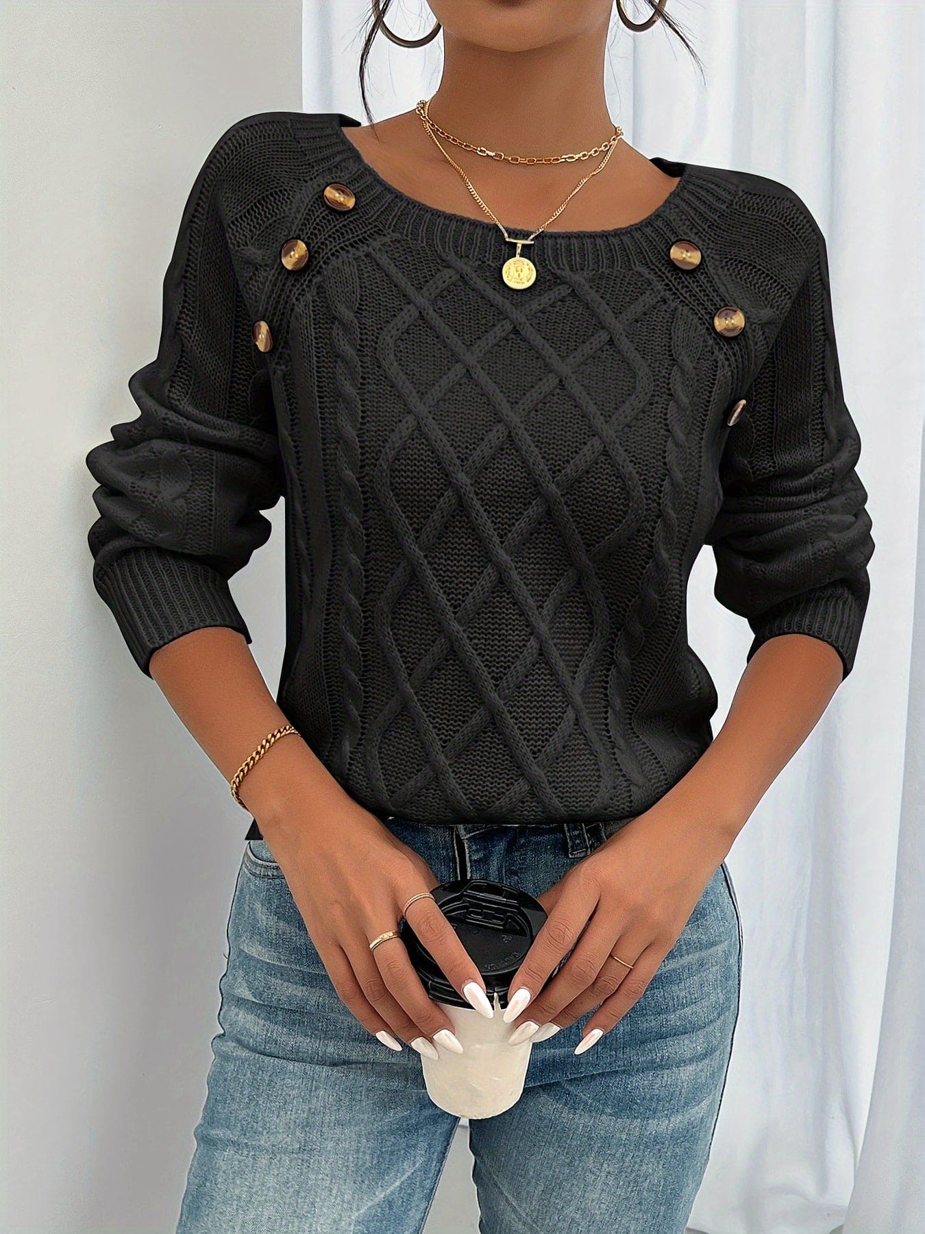 Kvinde iført beige strikket sweater med kabelstruktur og knapper ved skulderen, kombineret med lyse jeans_2