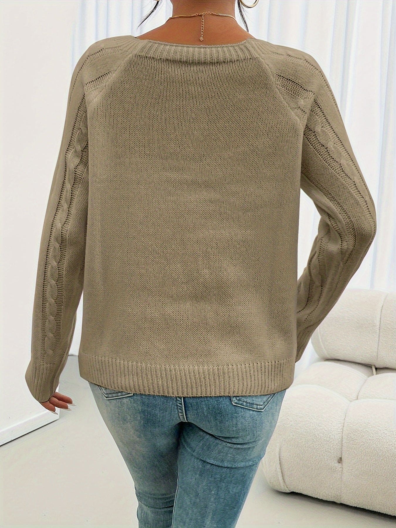 Kvinde iført beige strikket sweater med kabelstruktur og knapper ved skulderen, kombineret med lyse jeans_4