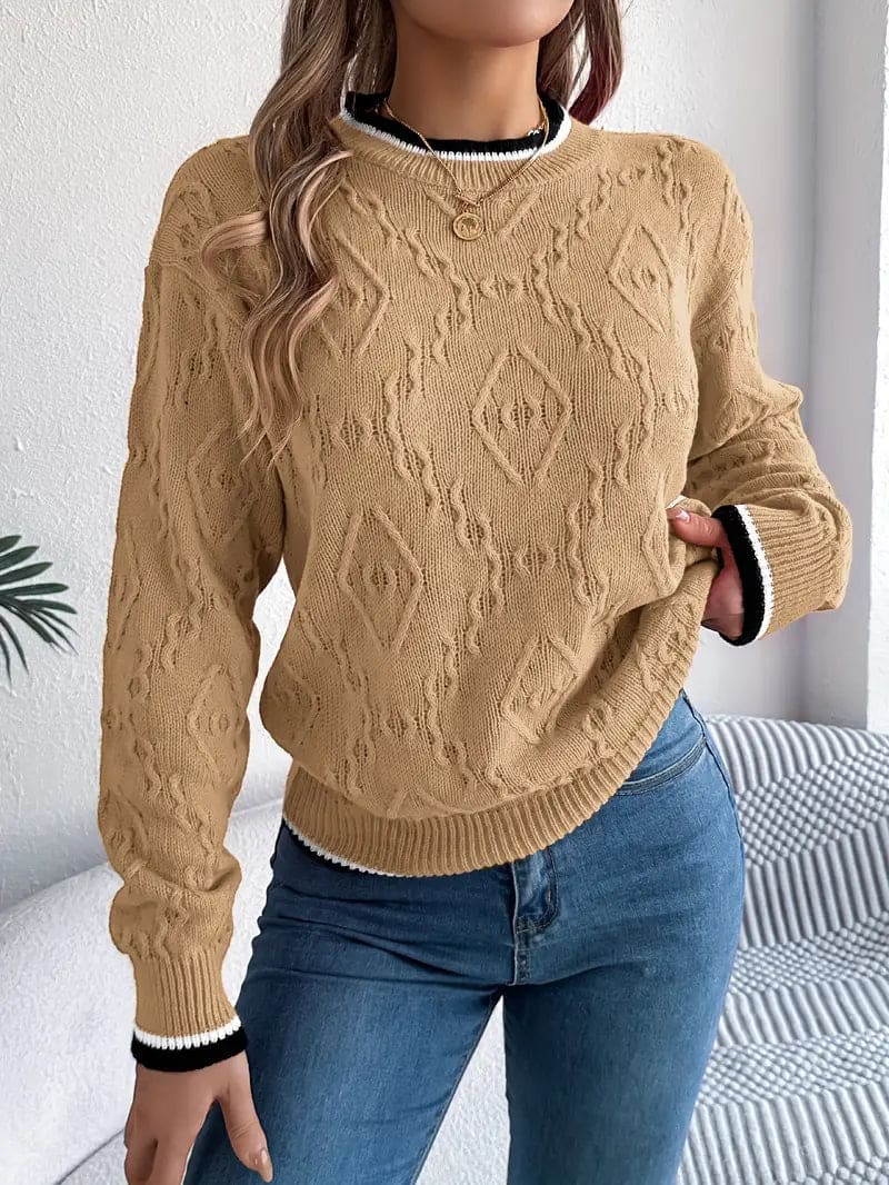 Kvinde iført beige strikket sweater med kontrastdetaljer og jeans foran lys baggrund_1