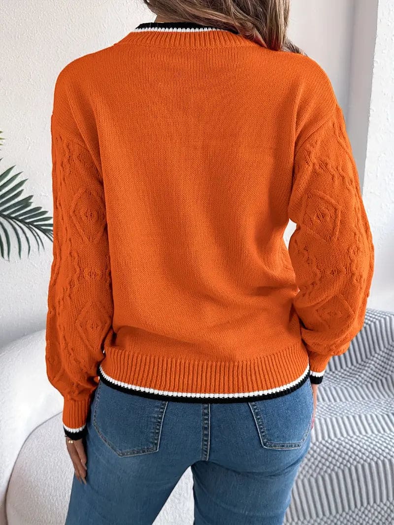 Kvinde iført beige strikket sweater med kontrastdetaljer og jeans foran lys baggrund_10