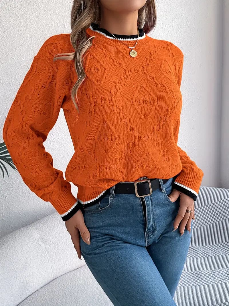 Kvinde iført beige strikket sweater med kontrastdetaljer og jeans foran lys baggrund_11
