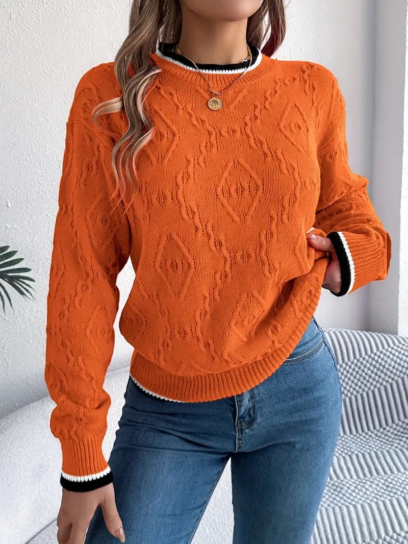 Kvinde iført beige strikket sweater med kontrastdetaljer og jeans foran lys baggrund_13