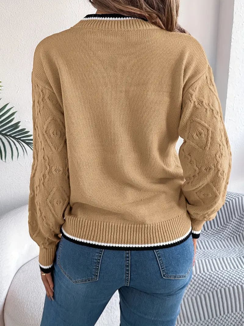 Kvinde iført beige strikket sweater med kontrastdetaljer og jeans foran lys baggrund_14