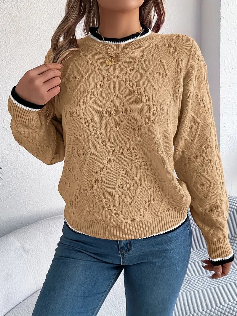 Kvinde iført beige strikket sweater med kontrastdetaljer og jeans foran lys baggrund_17