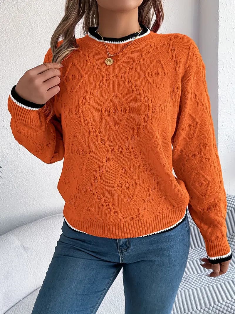 Kvinde iført beige strikket sweater med kontrastdetaljer og jeans foran lys baggrund_9