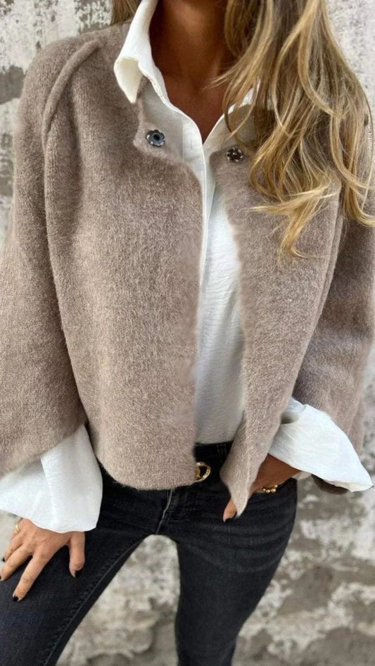 Kvinde iført en strikket sweater med hvid skjortekrave og manchetter samt dekorative knapper ved skulderen_0