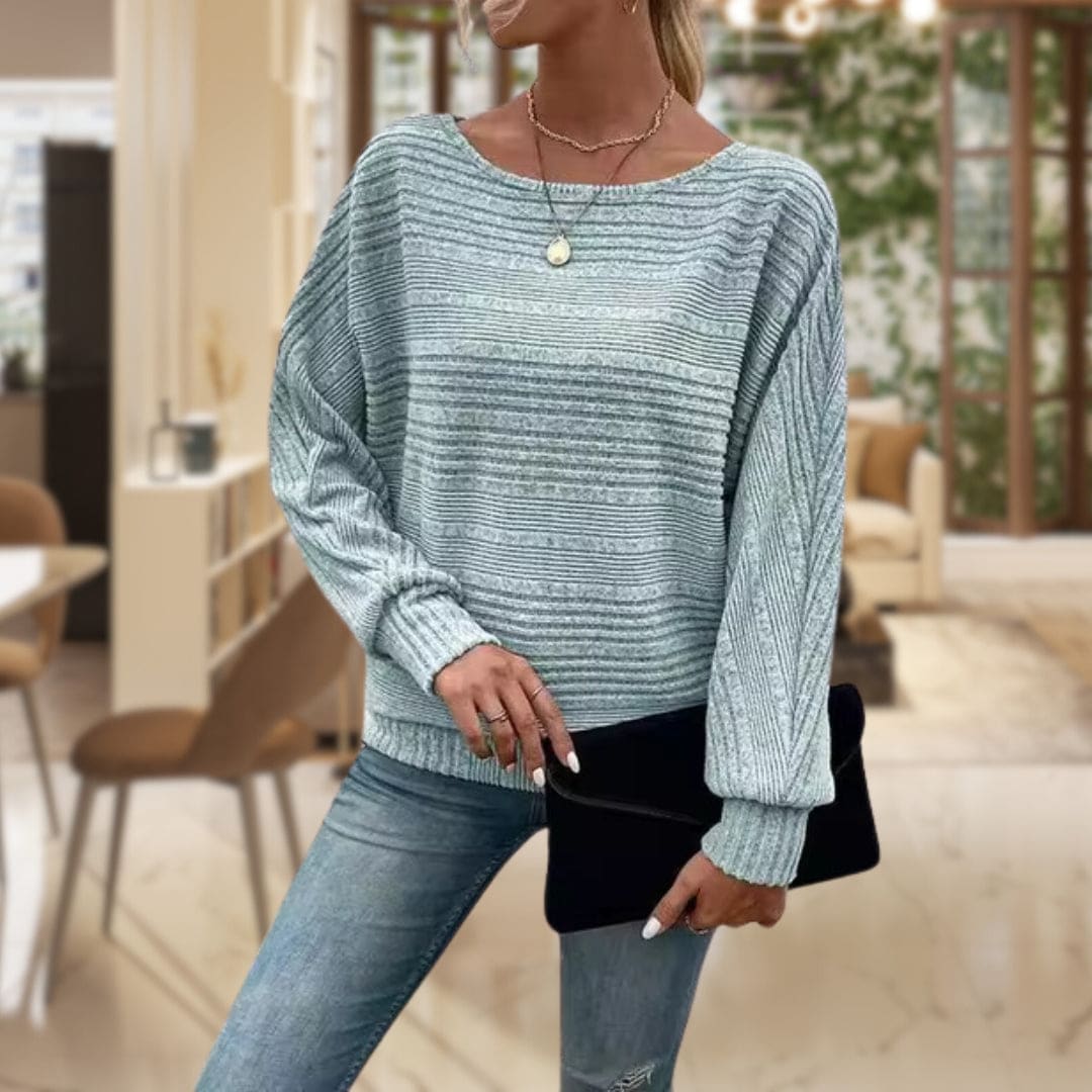 Model iført en lys struktureret sweater med rillestrik og afslappet pasform, stylet med jeans og lagdelte halskæder_0